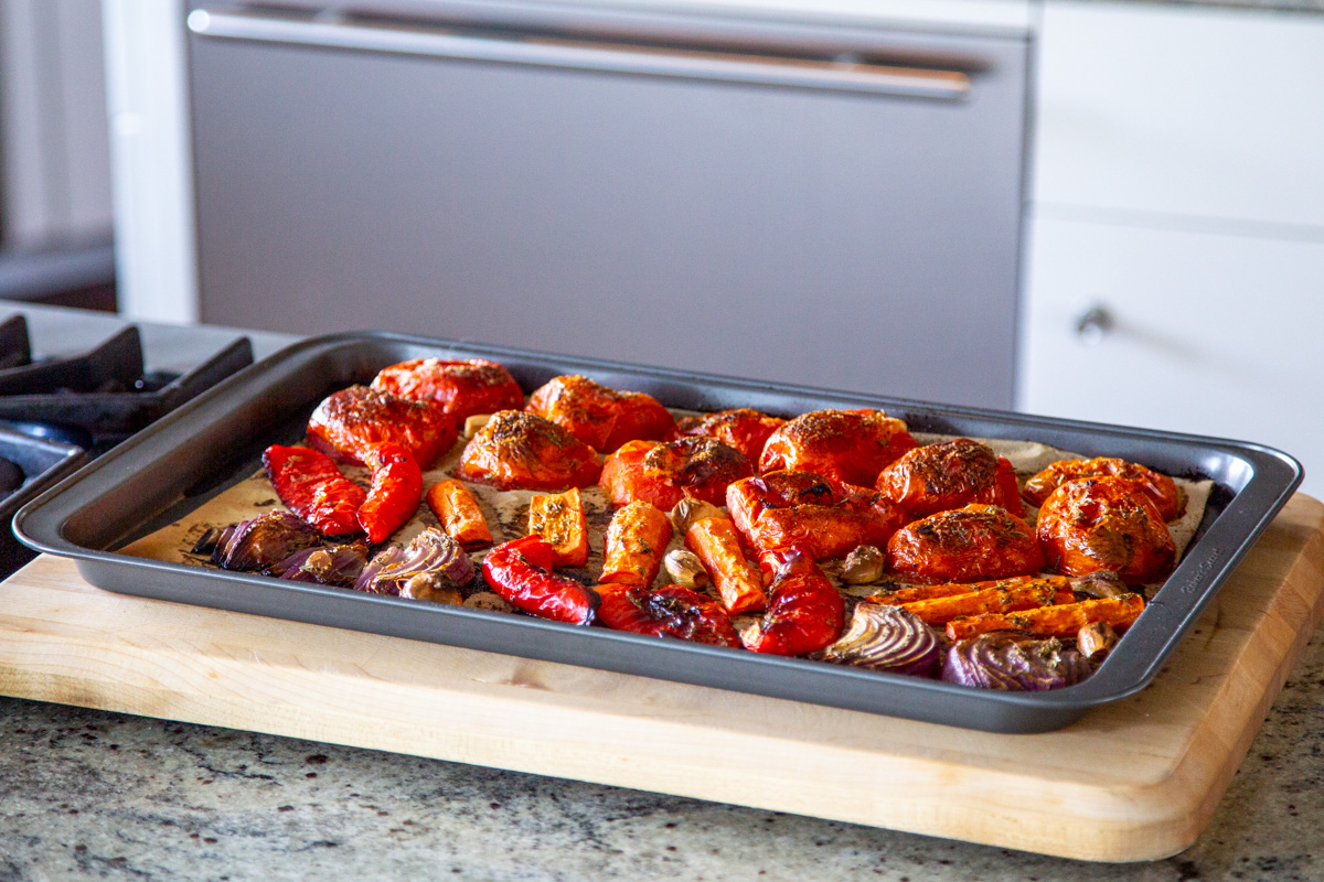 roasted bell peppers, tomatoes, garlic and onions on a baking sheet