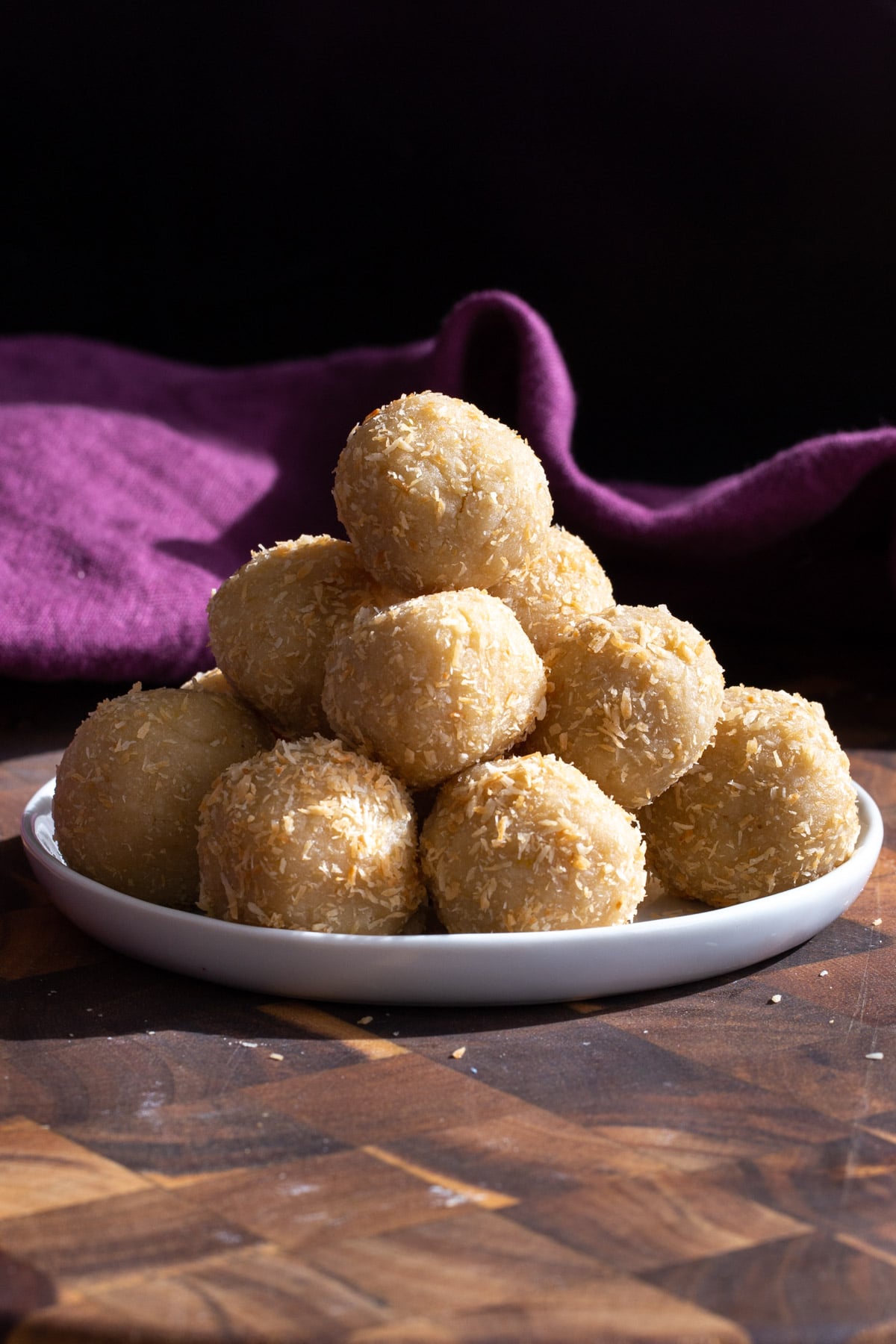 lemon coconut energy bites on a small white plate with a purple napkin in the background 