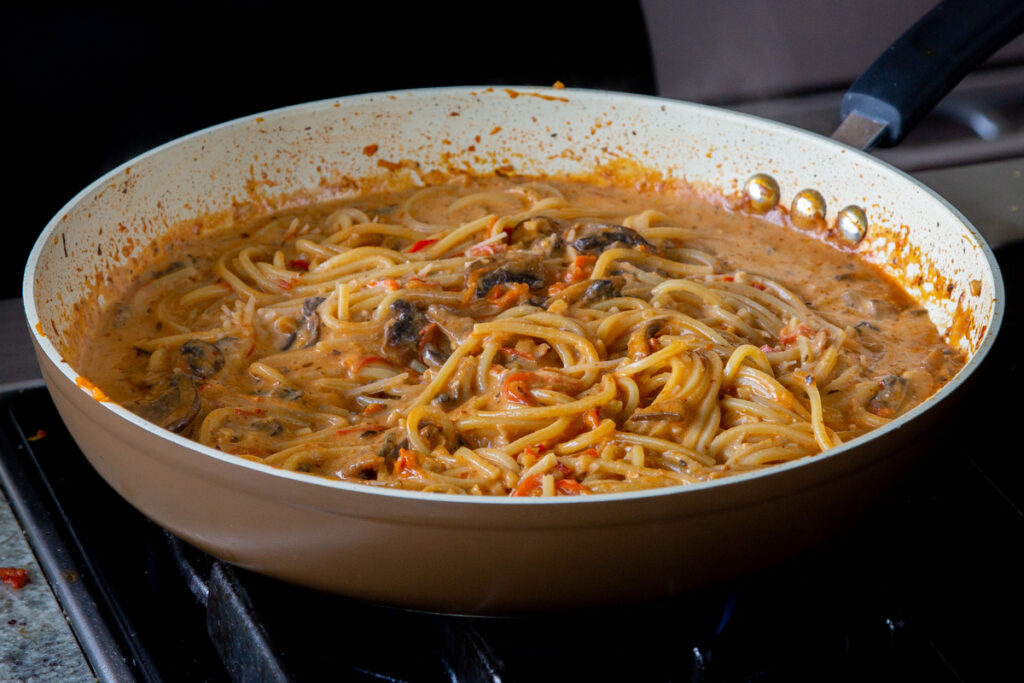 harissa pasta in the frying pan, after stirring in the non-dairy cream