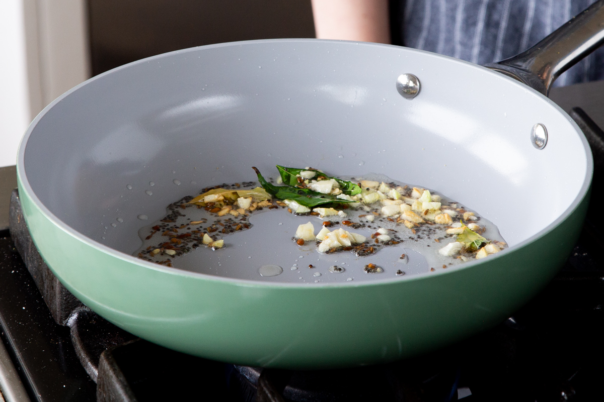 adding garlic and spices to the tempering in the pan