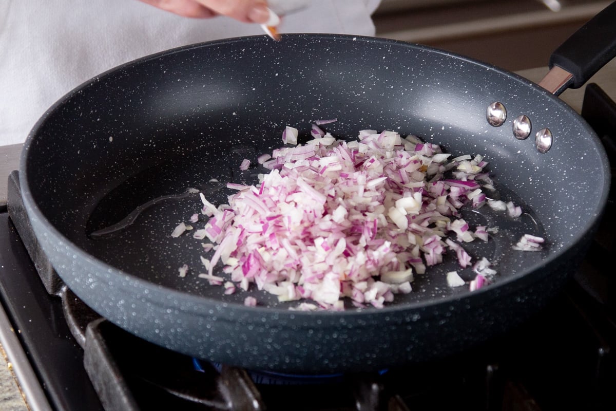 adding onion to the frying pan