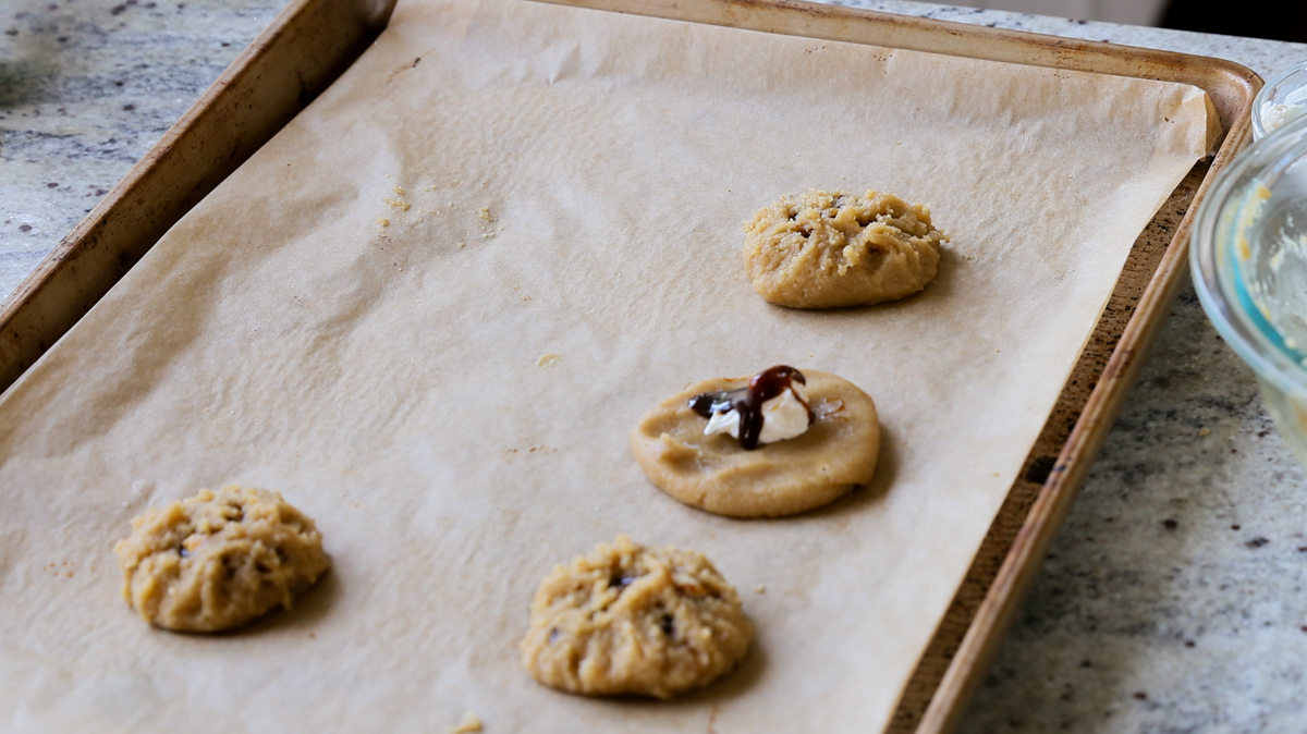 adding the caramel sauce over the cream cheese in one open cookie