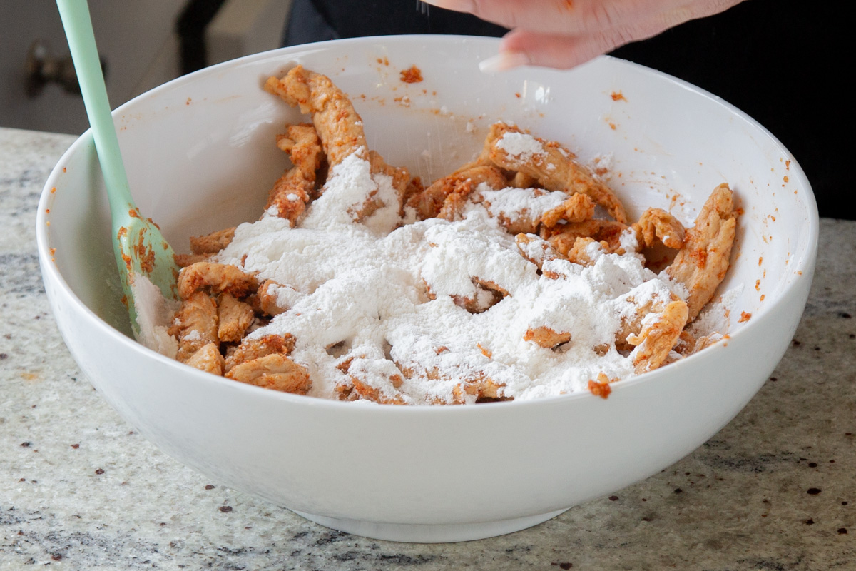adding cornstarch, baking powder, and flour to the bowl of soy curls