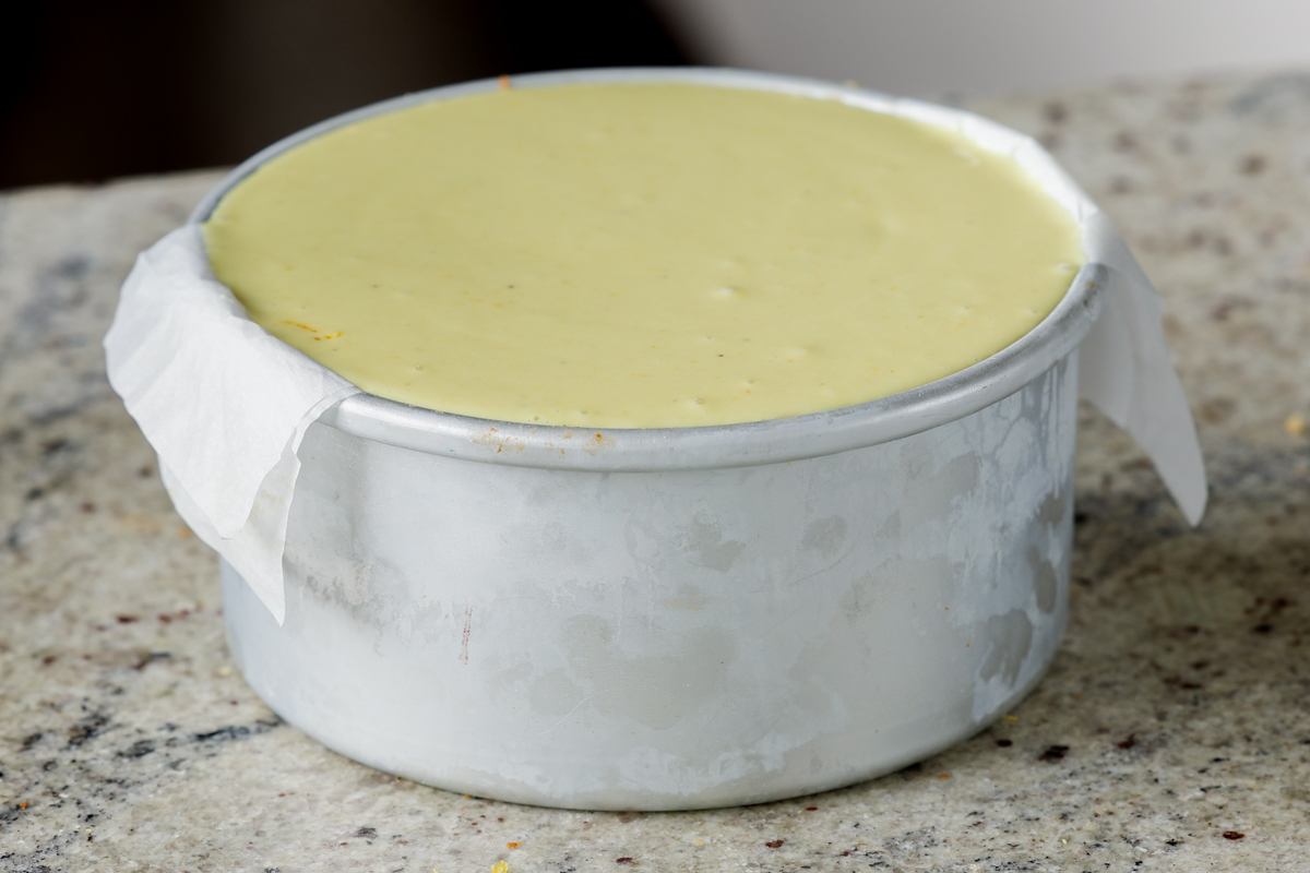 adding the second layer of frosting to the cakes in the pan