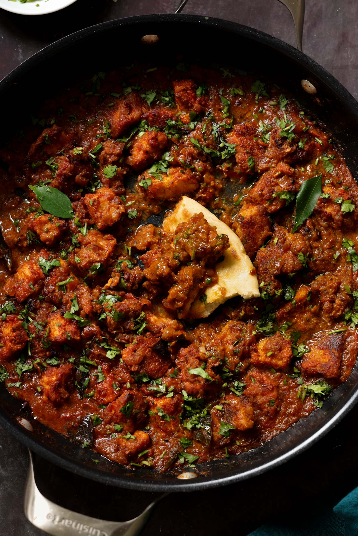 Madurai Chicken Curry in the pan with a piece of flatbread in it