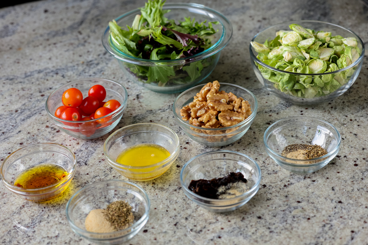 Brussels sprouts salad ingredients in bowls on a kitchen counter