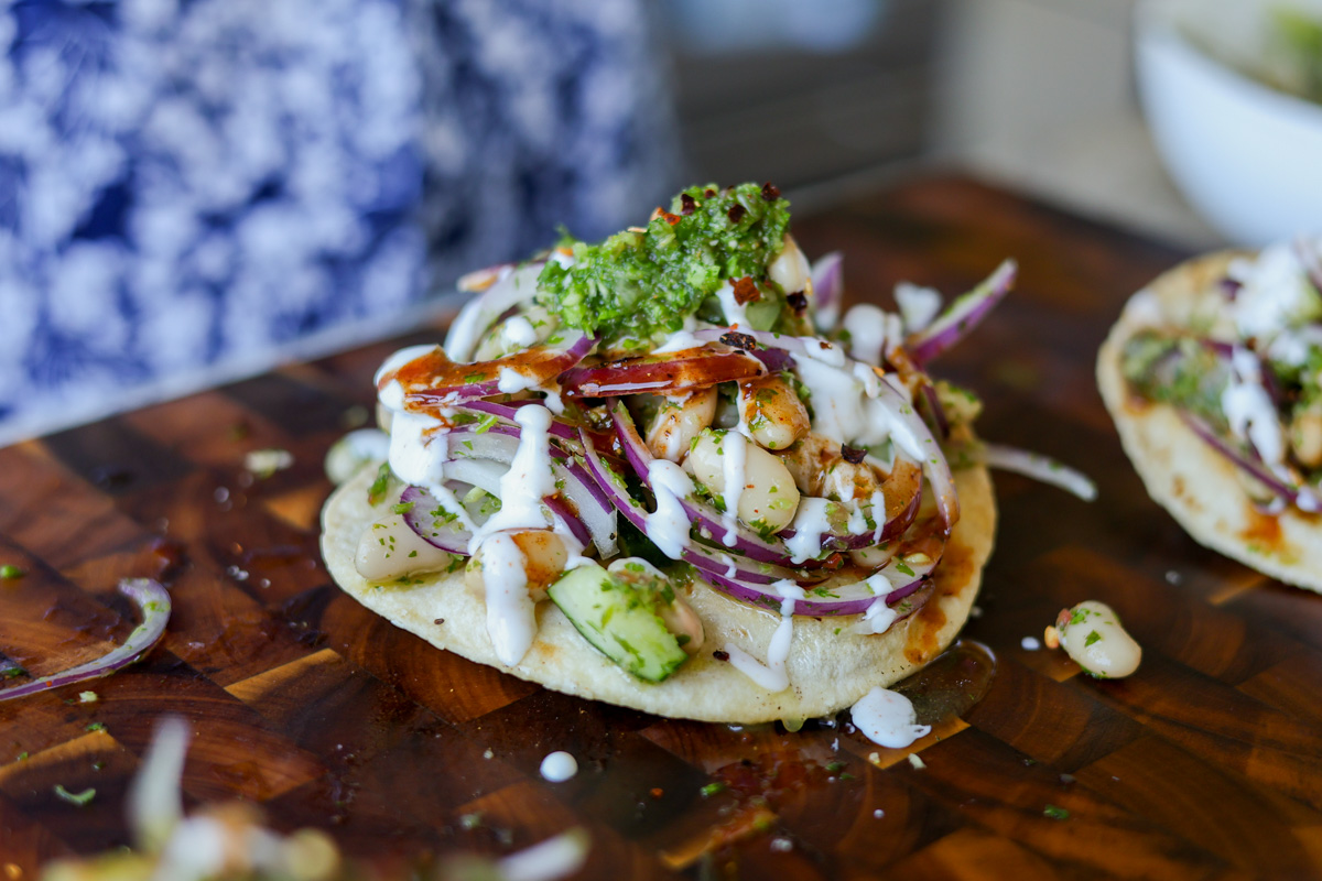 adding garnishes to the chutney white bean tostadas
