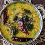Mango dal in a silver dish topped with chilis.