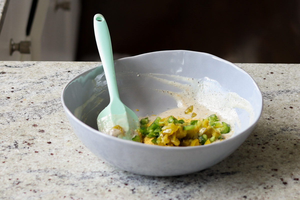 adding jalapeños and seasoning to the bowl