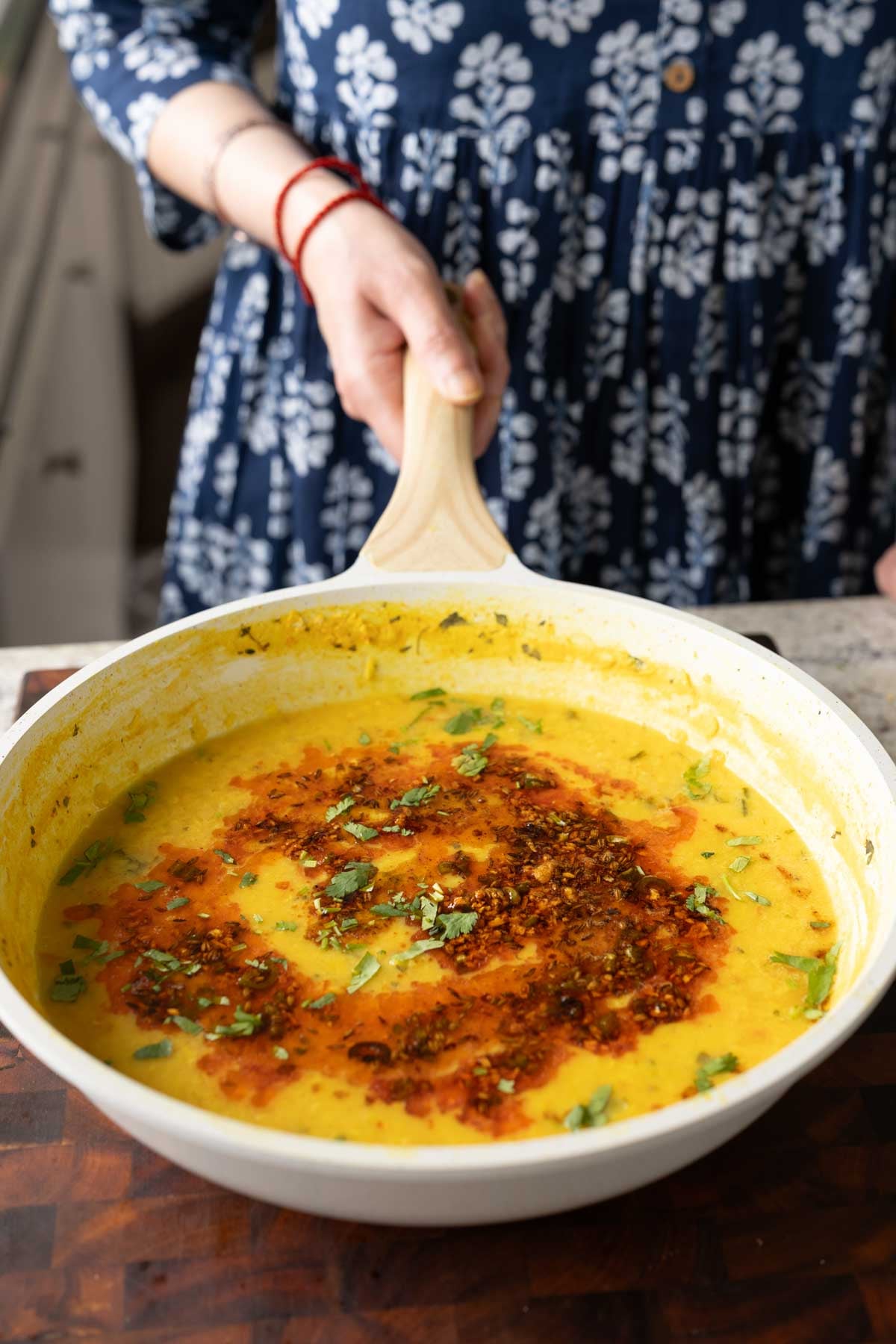 hand holding a pan of jeera dal