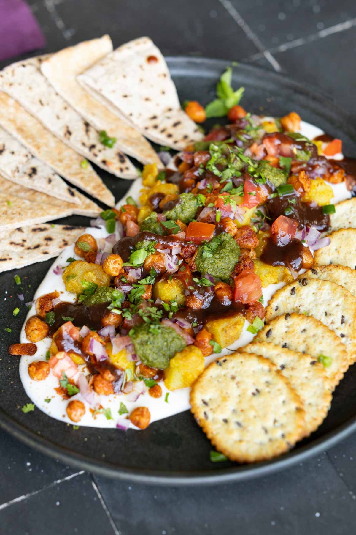 samosa platter with yogurt bed on a Black plate